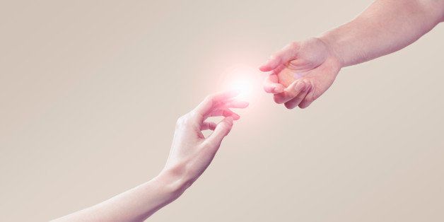 two hands connecting with light aura