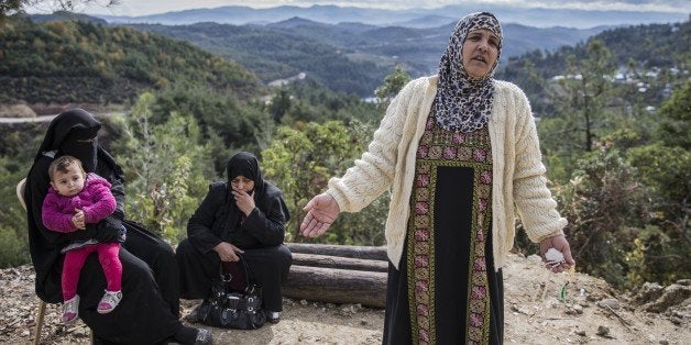 LATTAKIA, SYRIA - DECEMBER 02: Women, who had to fled their homes because of the air attacks of Assad regime and Russia, are seen near their children as they rest on their way to Turkey border in Lattakia, Syria on December 2, 2015. Areas in Syria in the Turkmen region of the Bayirbucak where Assad and Russia's warplanes have targeted civilian residential areas with air attacks have become ghost towns. (Photo by Fatih Aktas/Anadolu Agency/Getty Images)