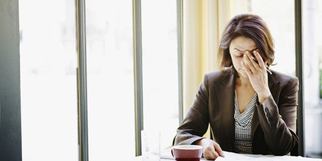 Businesswoman sitting at table in restaurant with head resting on hand