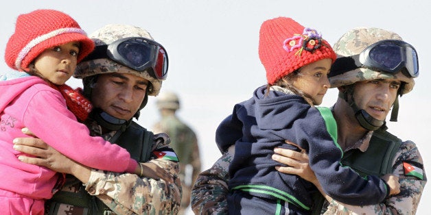 TOPSHOT - Jordanian security forces help Syrian girls after crossing from Syria into Jordan, at the Hadalat border crossing,