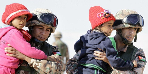 TOPSHOT - Jordanian security forces help Syrian girls after crossing from Syria into Jordan, at the Hadalat border crossing, east of the Jordanian capital Amman, on January 14, 2016.The number of Syrian refugees stuck on the border with Jordan has climbed from 12,000 to nearly 16,000 since December, the kingdom's government spokesman said on January 11. / AFP / KHALIL MAZRAAWI (Photo credit should read KHALIL MAZRAAWI/AFP/Getty Images)