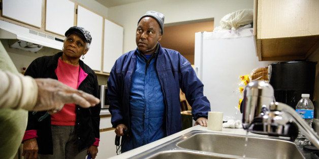 FLINT, MI - JANUARY 21: Fred the handyman explains the new water filter to Mary Stewart and Terrence Tyler at their residence in Shiloh Commons January 21, 2016 in Flint, Michigan. The city's water supply had been contaminated by lead after a switch from Lake Huron to the Flint river as a source in April, 2014. At a local fire station, residents were provided with water testing jugs, filters and clean water brought in by the National Guard. Residents also brought in water samples from their homes which would be sent out for lead testing. (Photo by Sarah Rice/Getty Images)