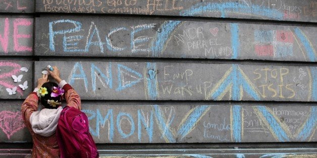 TOPSHOT - A woman sticks plastic butterfly decorations near peace messages at a makeshift memorial on the Place de la Bourse