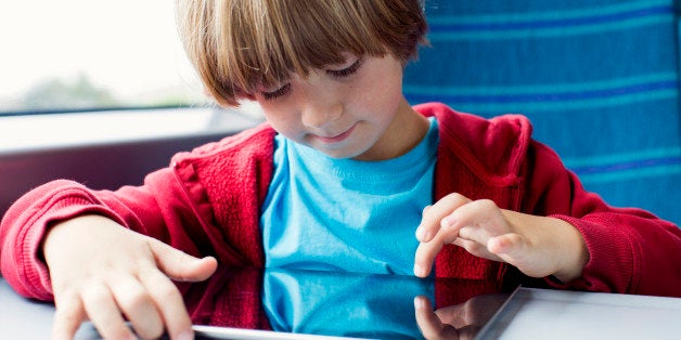 Young boy uses his tablet whilst travelling by train