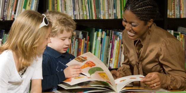 Woman and girl teaching boy to read