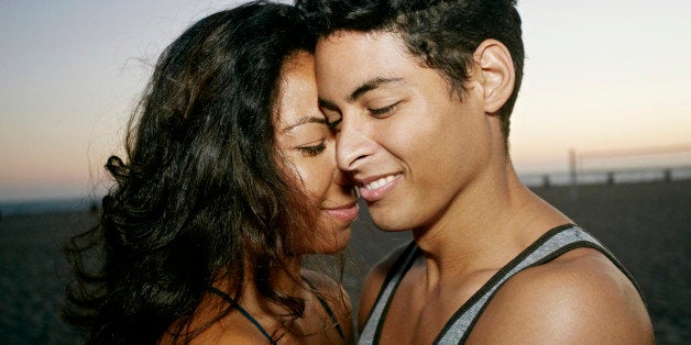 Hispanic couple hugging on beach