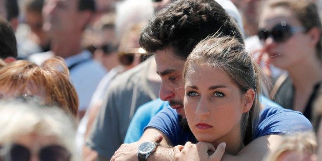 People observe a minute of silence on the famed Promenade des Anglais in Nice, southern France, to honor the victims of an attack near the area where a truck mowed through revelers, Monday, July 18, 2016. France is holding a national moment of silence for 84 people killed by a truck rampage in Nice, and thousands of people are massed on the waterfront promenade where Bastille Day celebrations became a killing field.(AP Photo/Francois Mori)