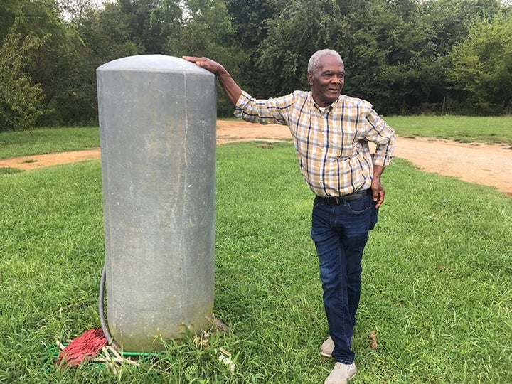 Booker Gipson leans against the tank his family uses for water. The 77-year-old grandfather is concerned the landfill across the street is having negative impacts on water and air in his neighborhood. The family was told to boil their water before drinking it. 