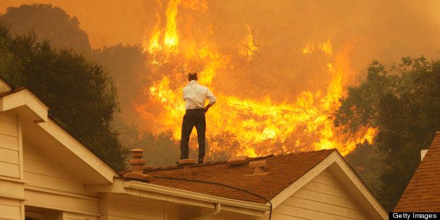 CAMARILLO, CA - MAY 3: A man on a rooftop looks at approaching flames as the Springs fire continues to grow on May 3, 2013 near Camarillo, California. The wildfire has spread to more than 18,000 acres on day two and is 20 percent contained. (Photo by David McNew/Getty Images)