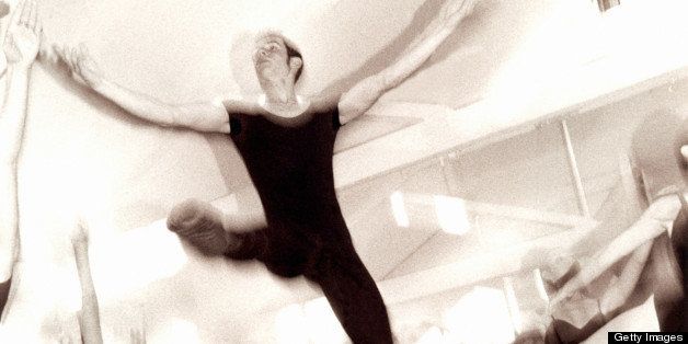 Ballet dancers practicing in dance studio with male dancer leaping in air