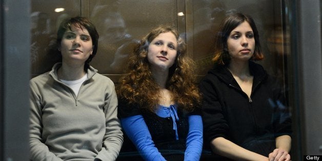 -- EDITORS NOTE -- CORRECTING POSITION --Members of the all-girl punk band 'Pussy Riot' (L-R) Yekaterina Samutsevich, Maria Alyokhina and Nadezhda Tolokonnikova sit in a glass-walled cage in a court in Moscow, on October 10, 2012. Russian appeals court ordered today the release of one member of anti-Vladimir Putin punk band Pussy Riot ,Yekaterina Samutsevich, 30, after giving her a suspended term but ordered two others, Maria Alyokhina, 24, and Nadezhda Tolokonnikova, 22, serve two years in a prison camp. AFP PHOTO / NATALIA KOLESNIKOVA (Photo credit should read NATALIA KOLESNIKOVA/AFP/GettyImages)