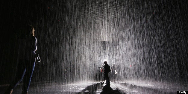 NEW YORK, NY - MAY 15: Visitors gather in the new 'Rain Room' installation at the Museum of Modern Art (MoMA) in Manhattan on May 15, 2013 in New York City. The 5,000 square-foot installation creates a field of falling water that stops in the area where people walk through, allowing them to remain dry. The piece, created by Random International, releases a 260-gallon per minute shower around visitors. (Photo by Mario Tama/Getty Images)