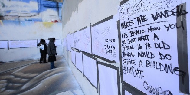 People write messages at New York's graffiti iconic spot '5Pointz' as it stands defaced with white paint covering most of the art work, after the building was painted white in New York, November 19, 2013. 5Pointz, a renowned heaven for urban graffiti artists, is set to be demolished by the end of the year to make way for luxury appartments. AFP PHOTO/Emmanuel Dunand (Photo credit should read EMMANUEL DUNAND/AFP/Getty Images)