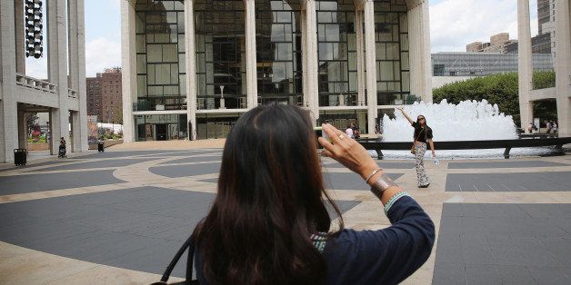 NEW YORK, NY - JULY 29: People pose for photos in front of the Metropolitan Opera on July 29, 2014 at Lincoln Center in New York City. The Metropolitan Opera's general manager Peter Gelb has threatened a lockout at the end of July if there is no an agreement with unions to that represent musicians, stagehands and other employees. (Photo by John Moore/Getty Images)