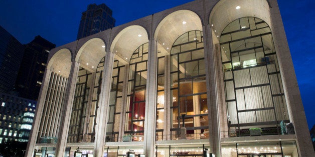 Pedestrians mill about the Metropolitan Opera house at Lincoln Center in the afterglow, Friday, Aug. 1, 2014, in New York. (AP Photo/John Minchillo)