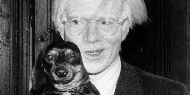 Pop artist Andy Warhol poses with a small dog in 1974. (AP Photo)