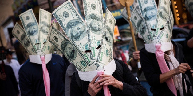 NEW YORK, NY - SEPTEMBER 17: Occupy Wall Street protesters wearing masks made out of enlarged dollar bills act in a short skit in Times Square on September 17, 2013 in New York City. Today marks the two year anniversary since the protestors set up camp in New York's financial district, calling for drastic social and finanical reform. (Photo by Andrew Burton/Getty Images)