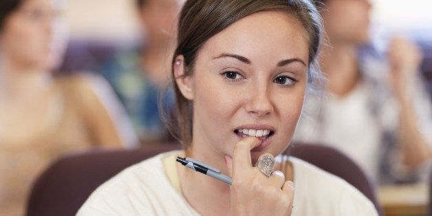 University student biting fingernail in lecture hall