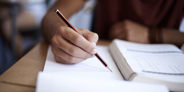 Closeup shot of a young man writing on a note pad