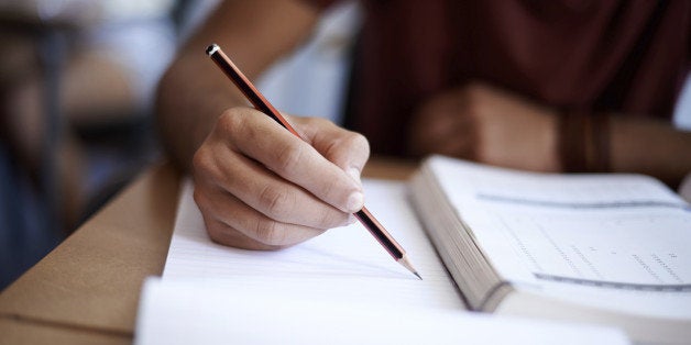 Closeup shot of a young man writing on a note pad