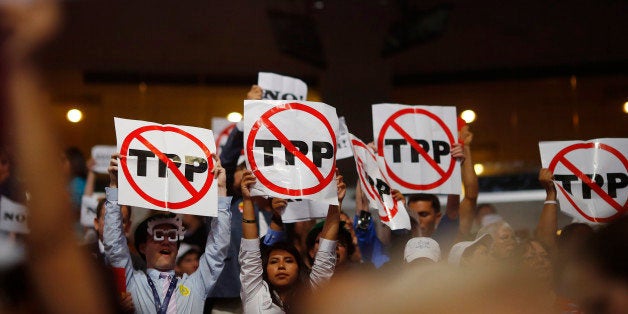 Alternate delegates protesting against the Trans Pacific Partnership (TPP) hold up signs during the first sesssion at the Dem