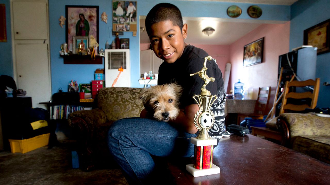 Cesar Gaspar at home with his dog and the championship soccer trophy he and his soccer team won in August.