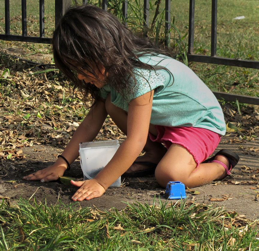 A child plays with dirt in the yard of a Townsend Street apartment complex where tests show the soil contains low levels of lead.