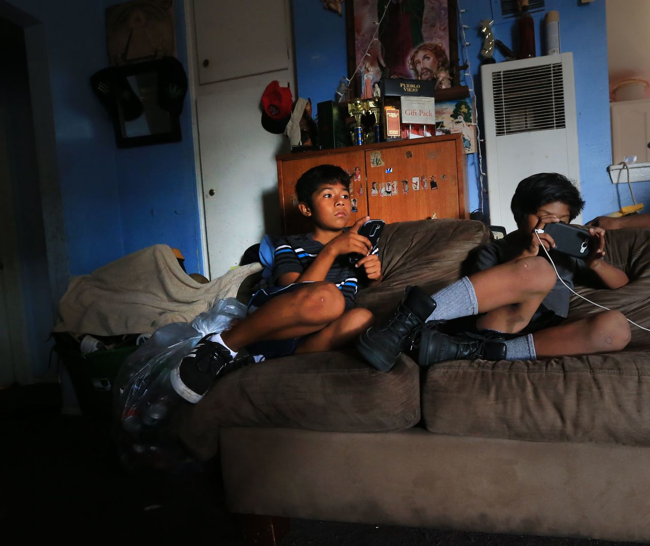 In September 2016, Cesar (left), 11, and his younger brother, Peter, 8, play games on their mobile phones in their Santa Ana apartment living room.