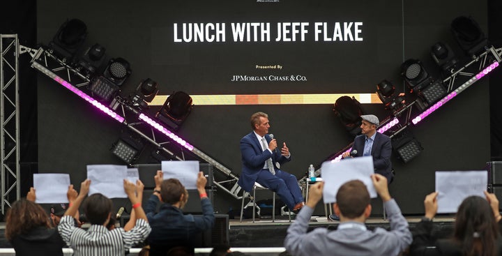 Sen. Jeff Flake (R-Ariz.) talks with the moderator at the Forbes Under 30 Summit in Boston on Monday as anti-Kavanaugh protes