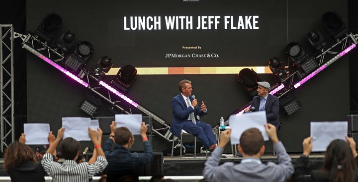 Sen. Jeff Flake (R-Ariz.) talks with the moderator at the Forbes Under 30 Summit in Boston on Monday as anti-Kavanaugh protesters urge him to oppose the Supreme Court nominee's confirmation.