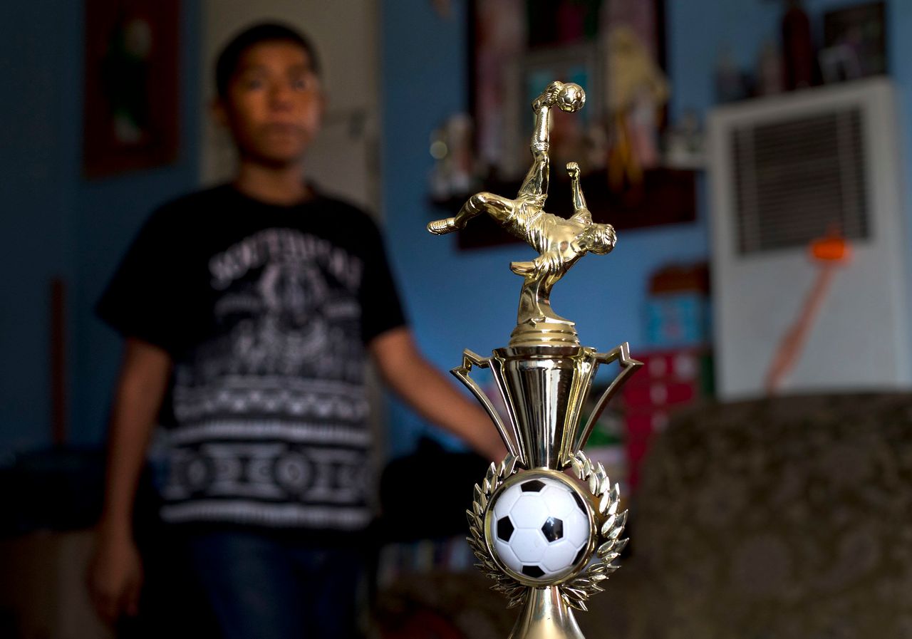 In August 2018, Cesar, 13, walks past the championship trophy he and his soccer team won.