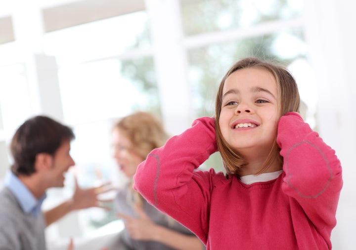 Child hiding her ears from parent's fight