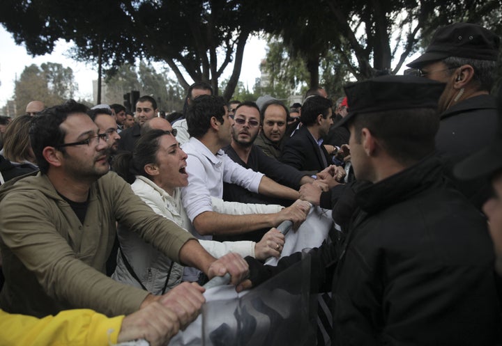 Employees of Cyprus' Laiki (Popular) Bank protest outside the parliament building in the capital Nicosia on March 22, 2013, as the east Mediterranean island' two biggest lenders urged lawmakers to adopt a tax on bank deposits, a controversial deal with the EU that the MPs rejected this week. AFP PHOTO/YIANNIS KOURTOGLOU (Photo credit should read Yiannis Kourtoglou/AFP/Getty Images)