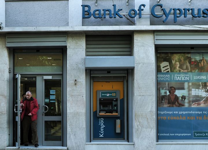 A man leaves a Bank of Cyprus branch in Athens on March 27, 2013, as Greek subsidiaries of three Cypriot banks reopened today after Greece's third lender, Piraeus bank, signed an agreement to acquire all their deposits, loans and branches. But banks in Cyprus itself remained closed as authorities worked out a plan to get them back up and running amid the country's financial crisis. AFP PHOTO/ LOUISA GOULIAMAKI (Photo credit should read LOUISA GOULIAMAKI/AFP/Getty Images)