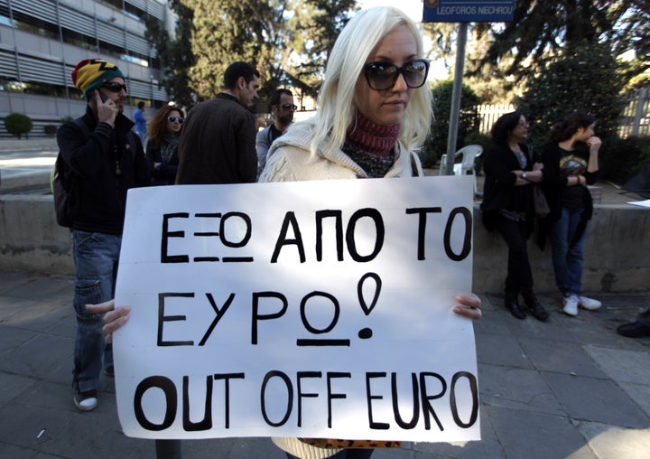 A Russian woman holding dual nationality holds a placard during a protest outside the parliament in Nicosia on March 24, 2013. Cyprus President Nicos Anastasiades entered emergency talks with the island's international creditors seeking to avert bankruptcy in a crisis that is again threatening the stability of the wider eurozone. AFP PHOTO/PATRICK BAZ (Photo credit should read PATRICK BAZ/AFP/Getty Images)