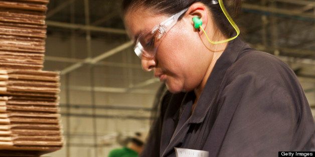 Hispanic woman packing boxes in factory