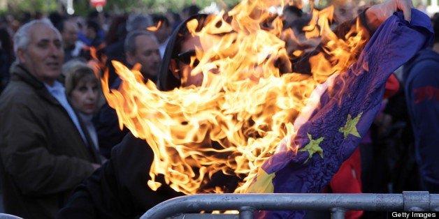 A demonstrator burns a European Union flag outside the parliament in the Cypriot capital, Nicosia, on April 4, 2013, following a protest by members of the bank employees' union ETYK over fears that pensions may be at risk under Cyprus's bailout, as more details emerged of biting austerity measures imposed on the cash-strapped island. AFP PHOTO / YIANNIS KOURTOGLOU (Photo credit should read Yiannis Kourtoglou/AFP/Getty Images)