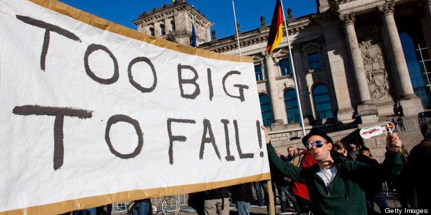 BERLIN, GERMANY - OCTOBER 15: Protesters demonstrating against the influence of bankers and financiers hold a banner reading 'Too big to fail' in front of the Reichstag building on October 15, 2011 in Berlin, Germany. Thousands of people took to the streets today in cities across Germany in demonstrations inspired by the Occupy Wall Street protests in the United States. Activists are demanding an end to the free-wheeling ways of global financial players whom they see as responsible for the current European and American economic woes. (Photo by Carsten Koall/Getty Images)