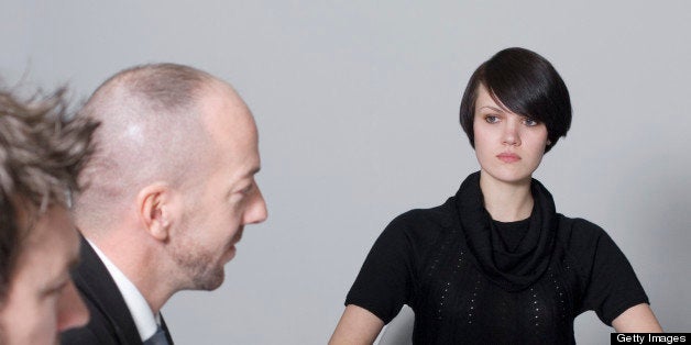 young woman sitting at conference table with two businessmen