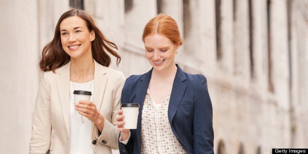 Smiling businesswomen walking with coffee