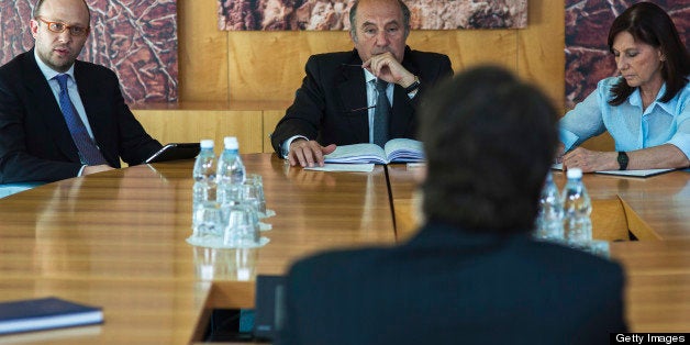 Business woman and two businessmen sitting by the table and interviewing a man sitting on the other side of the table, blurred foreground.