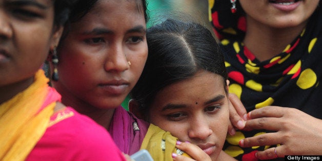 Bangladeshi garment workers, employed in the building which collapsed a fortnight ago killing hundreds, wait in line to claim their salaries in Savar on the outskirts of Dhaka, on May 8, 2013. Recovery teams have so far recovered 782 bodies and that figure is expected to rise still further as bulldozers continue to churn through the rubble. The typical Bangladeshi garment worker takes home less than 40 dollars a month, a wage that Pope Francis has condemned as akin to slave labour. AFP PHOTO/ Munir uz ZAMAN (Photo credit should read MUNIR UZ ZAMAN/AFP/Getty Images)