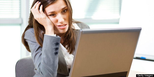 Young woman looking at the computer and boring or not happy about the news.