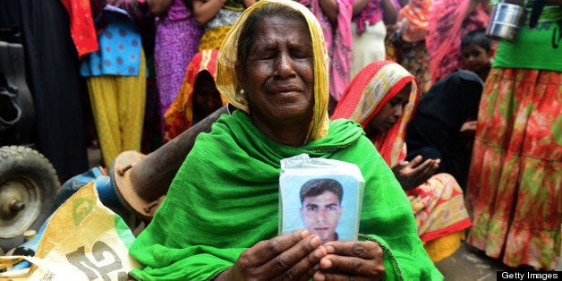 A Bangladeshi family member holds up the portrait of her missing relative as she offers prayers in front of the rubble of a nine-storey building collapse in Savar, on the outskirts of Dhaka on May 14, 2013. Bangladesh's army wrapped up its search May 14, 2013 for bodies in a collapsed nine-storey building outside the capital as dozens of people were still massed at the site for news of their missing relatives. AFP PHOTO/Munir uz ZAMAN (Photo credit should read MUNIR UZ ZAMAN/AFP/Getty Images)