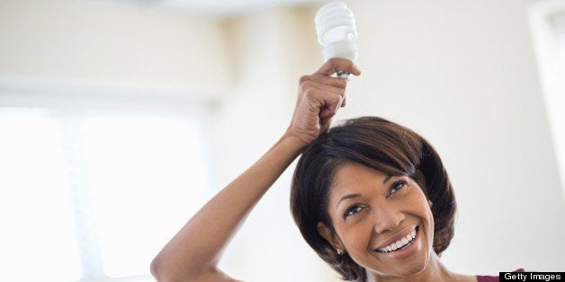 Happy mid adult businesswoman holding light bulb over head