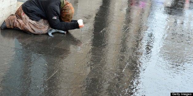 A beggar asks for money in a street of Rome on January 28, 2013. AFP PHOTO / GABRIEL BOUYS (Photo credit should read G