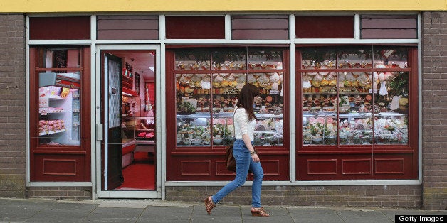 A pedestrian walks pass stickers applied to the windows of a former butcher?s shop in Belcoo, Northern Ireland, outside Enniskillen on June 1, 2013. The stickers give the premises the superficial appearance of a open business. More than 100 properties within range of the Lough Erne resort which hosts the G8 Summit have been tidied up, painted or power-hosed. Britain is hosting this year's summit on June 17-18. AFP PHOTO/ PETER MUHLY (Photo credit should read PETER MUHLY/AFP/Getty Images)