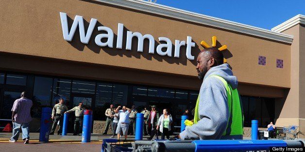 A Walmart employee gathers pushcarts as police man the front of a Walmart store amid heightened Black Friday security in Paramount, California on November 23, 2012 as Walmart employees and their supoorters protested nearby. The US retail giant Walmart admitted on November 27 some of its products were made at the Bangladesh garment factory that burnt down at the weekend killing 110 workers, as anger grows over lax safety standards. The fire broke out at the ground-floor warehouse of the multi-storey Tazreen Fashions factory 30 kilometres (18 miles) north of Dhaka on the night of November 24, trapping hundreds of workers on the upper upper floors, police said. AFP PHOTO / Frederic J. BROWN (Photo credit should read FREDERIC J. BROWN/AFP/Getty Images)