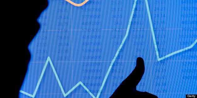 A man in silhouette gives the 'thumbs up' gesture as he looks at a stock chart graph on an LCD screen. Could also be a scientific chart.