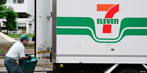 A delivery driver loads crates onto a Seven & I Holdings Co. truck displaying the 7-Eleven logo in Kawasaki City, Kanagawa Pr